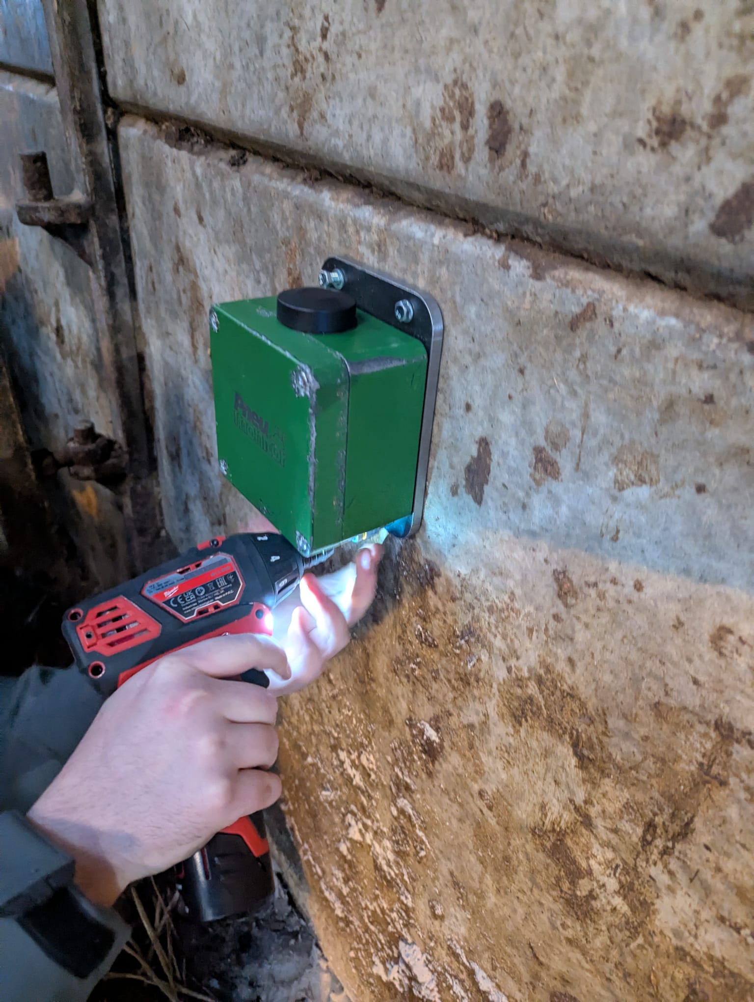 A Pneumonitor being fixed to a shed wall with a cordless drill